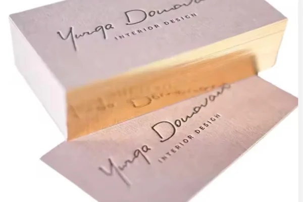 Elegant business cards with gold border and embossed text for luxury branding.