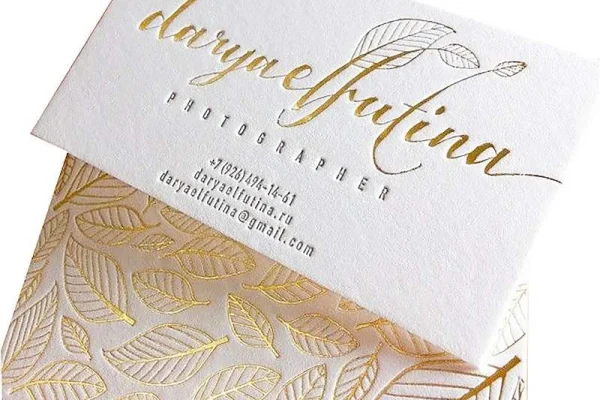 Luxury business card with gold foil and embossed leaf design for a photographer.