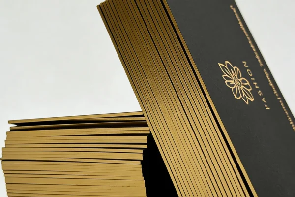Luxury business cards with gold edges and floral logo design.