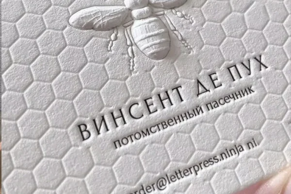 Embossed business card with bee design and contact details.